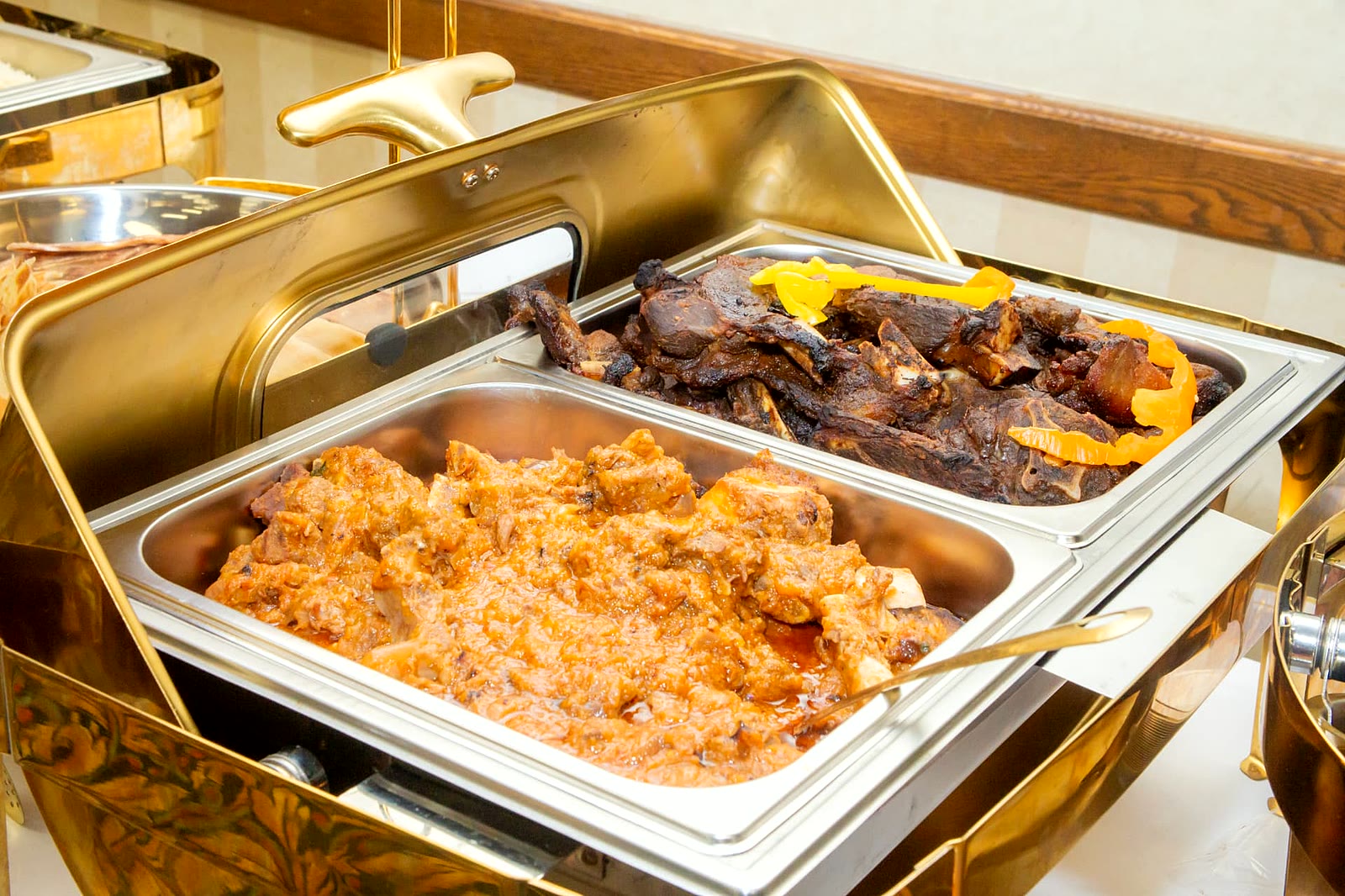 Beef wet fry and charcoal-roasted goat ribs with peppers in gold chafing dishes, North York catering