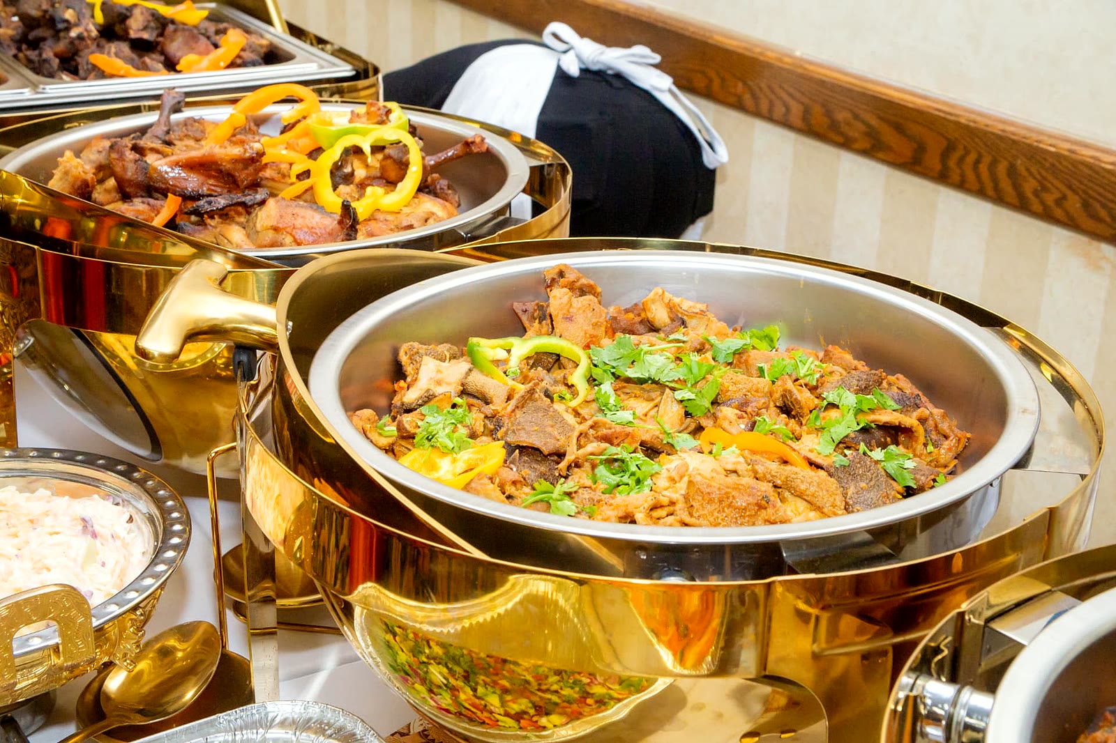 Slow-cooked goat stew finished with fresh coriander and peppers at a catered event in Toronto