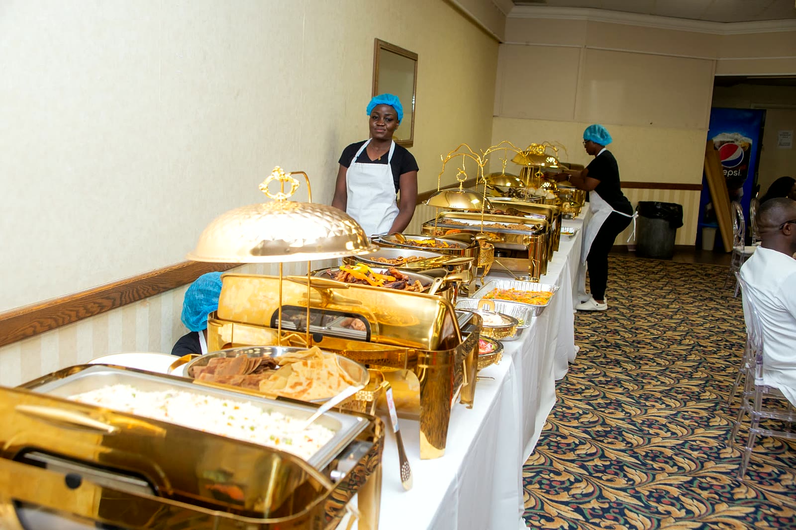 Uniformed catering staff attending a gold chafing dish buffet line in North York, Toronto