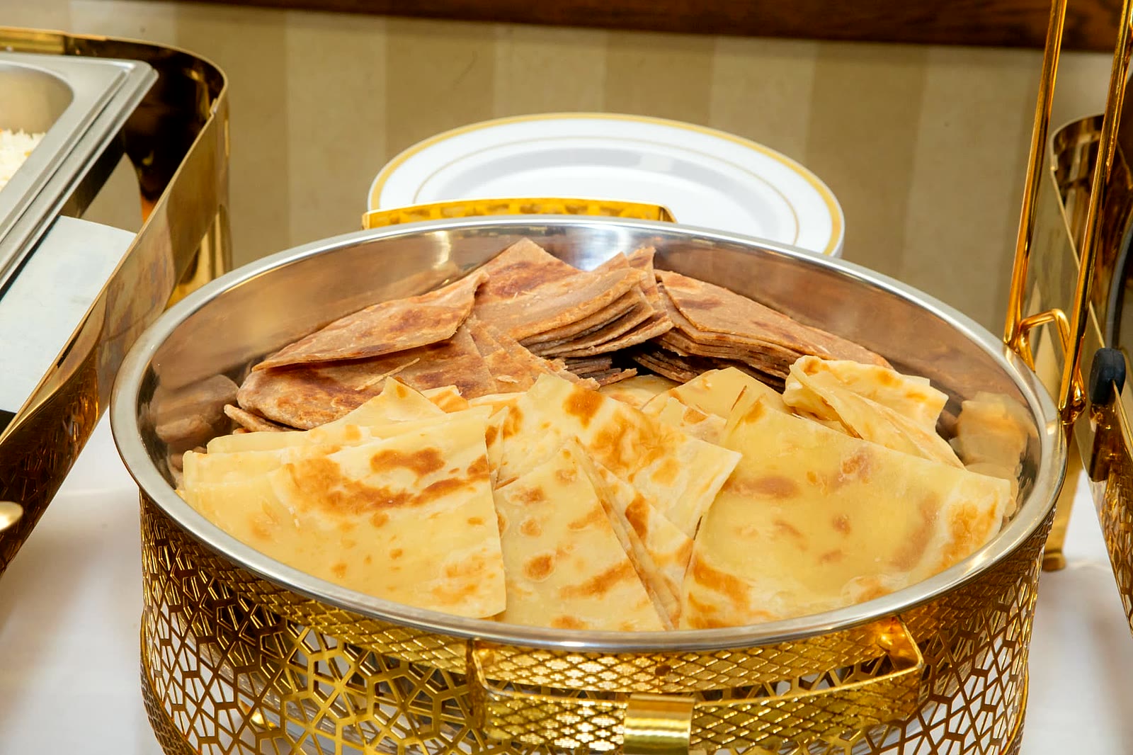 White and brown chapati flatbread stacked in a gold serving dish at a Toronto catered event