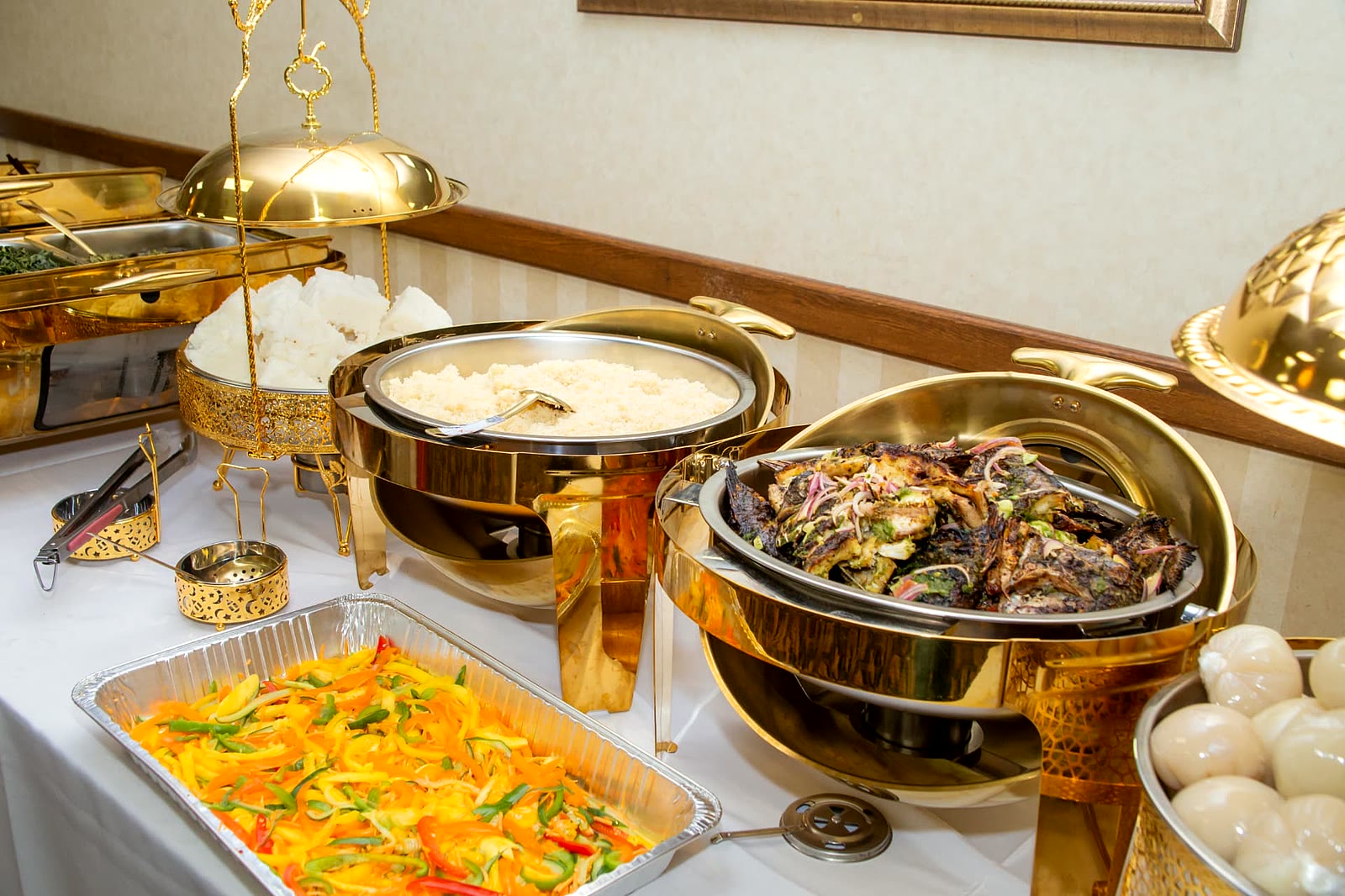 Grilled whole fish, steamed rice and sautéed peppers on a gold-dressed catering table in Toronto